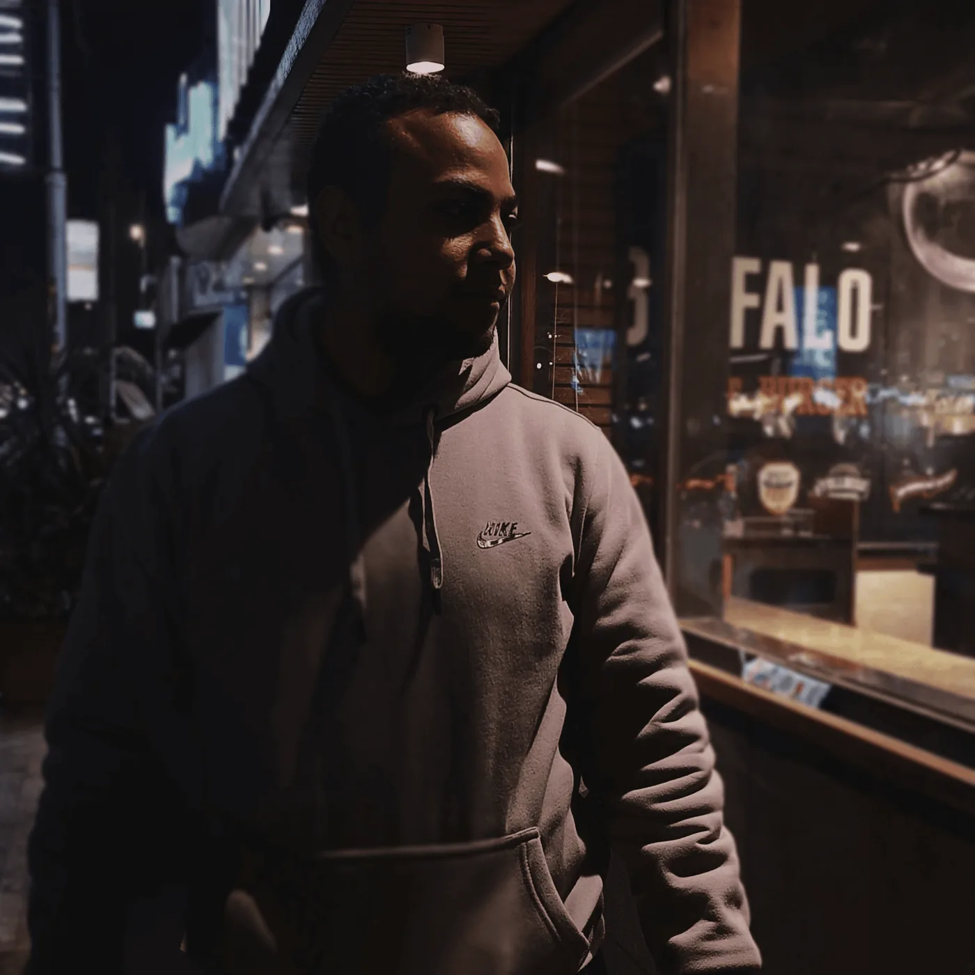 Sayed Elmarakpy at night, in a grey hoodie, outside a lit shopfront